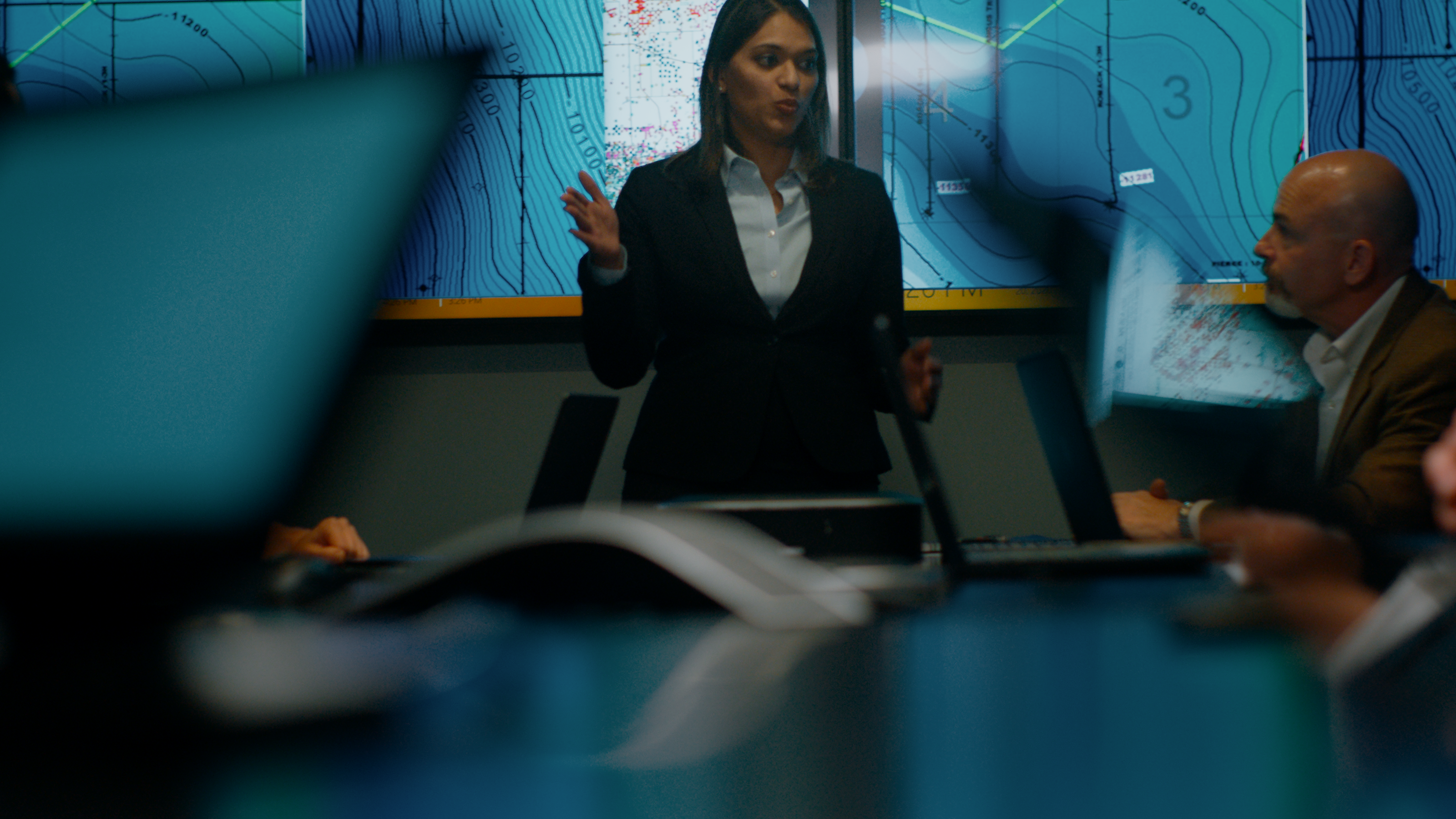 Female leading a group meeting with maps on screen