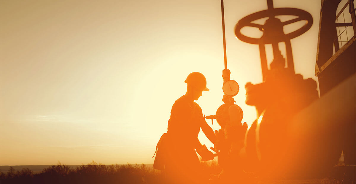 Oil worker is checking the oil pump on the sunset background.