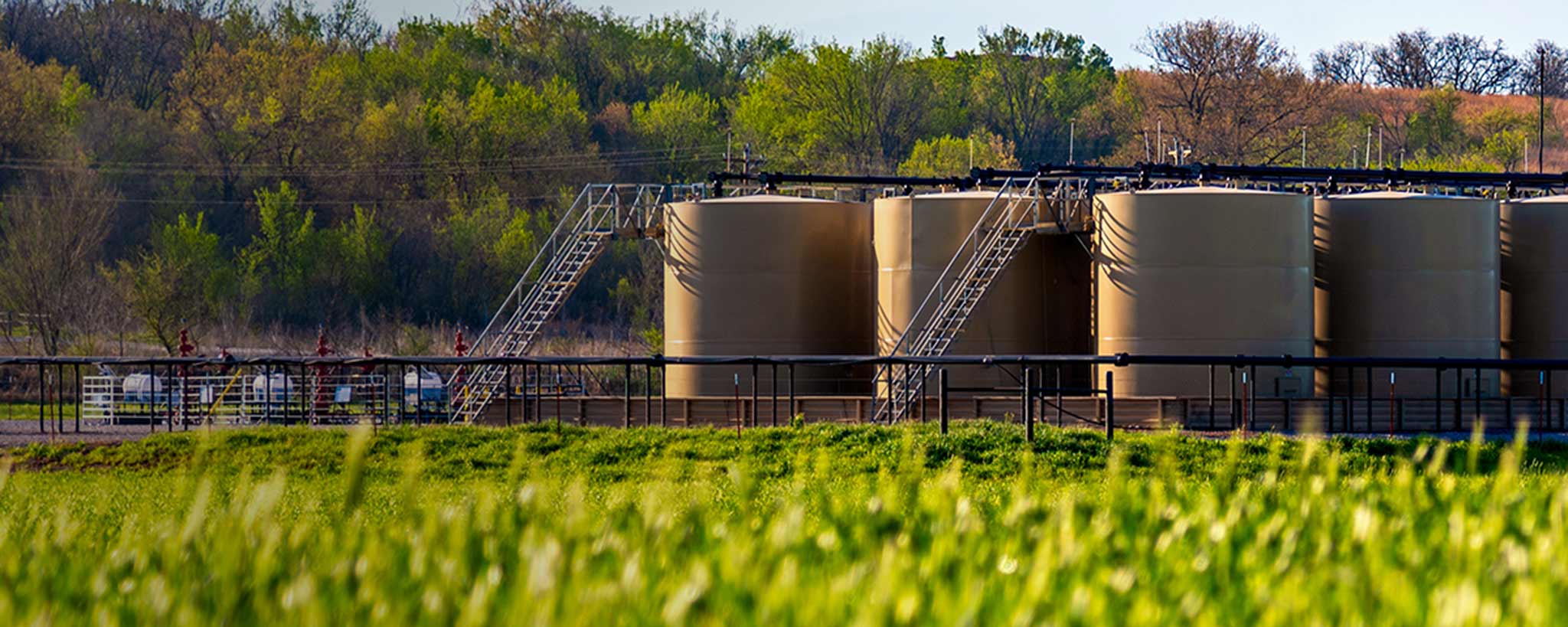 Tanks surrounded by fields of green crops and trees