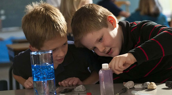 Two children experimenting with liquids in a science classroom