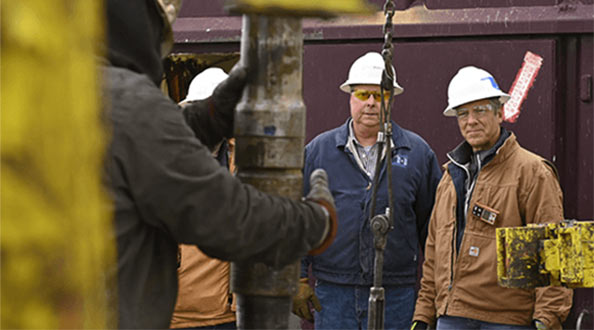 Mike Rowe with a technician observing a machine operator