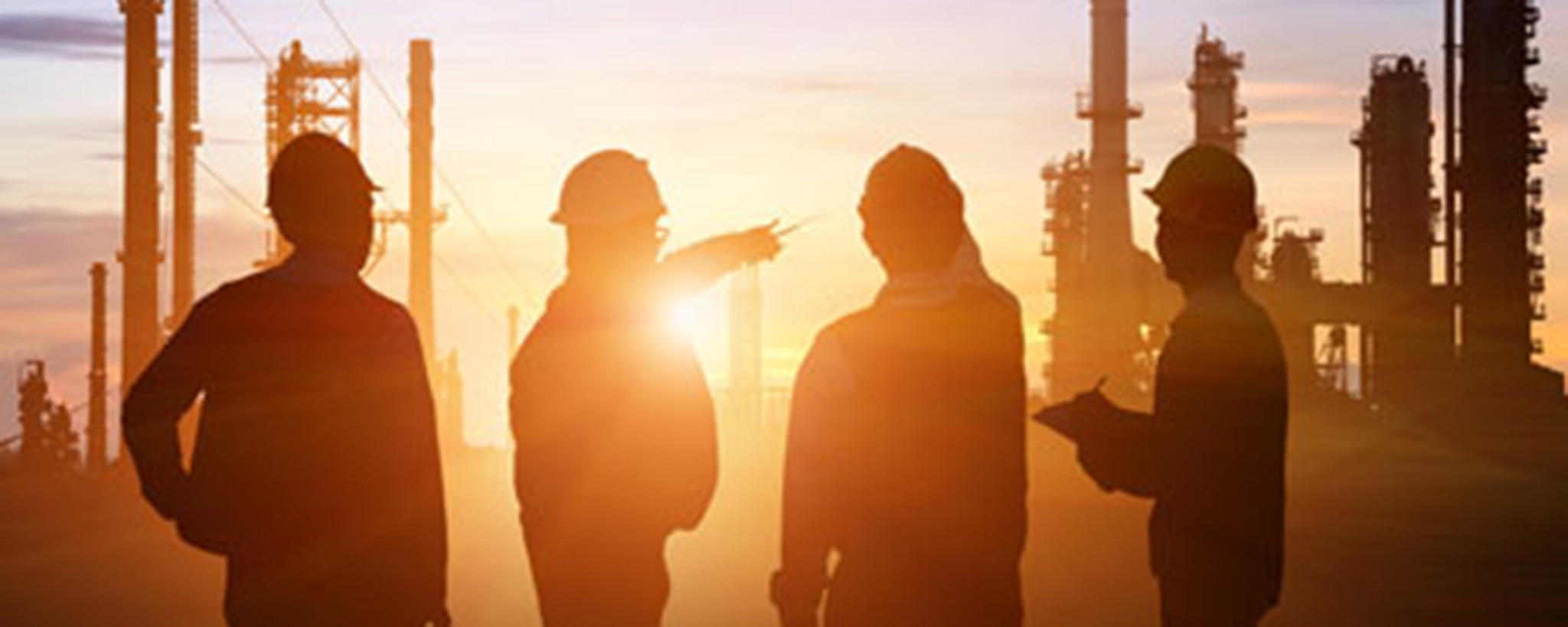 Oil workers inspecting an oil facility at sunrise