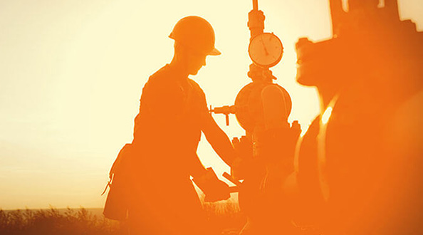 Oil worker checking the oil pump against a sunset background