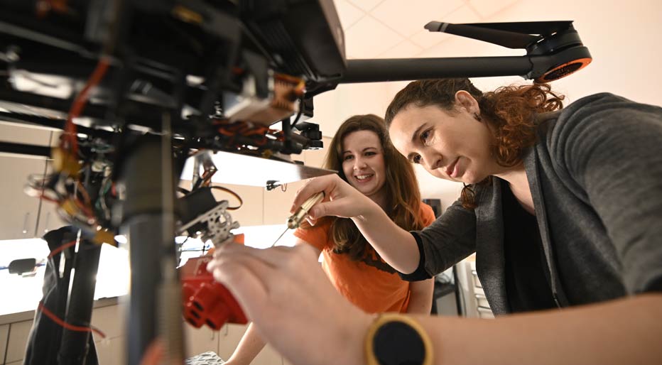 Technician repairing a part with a student observer