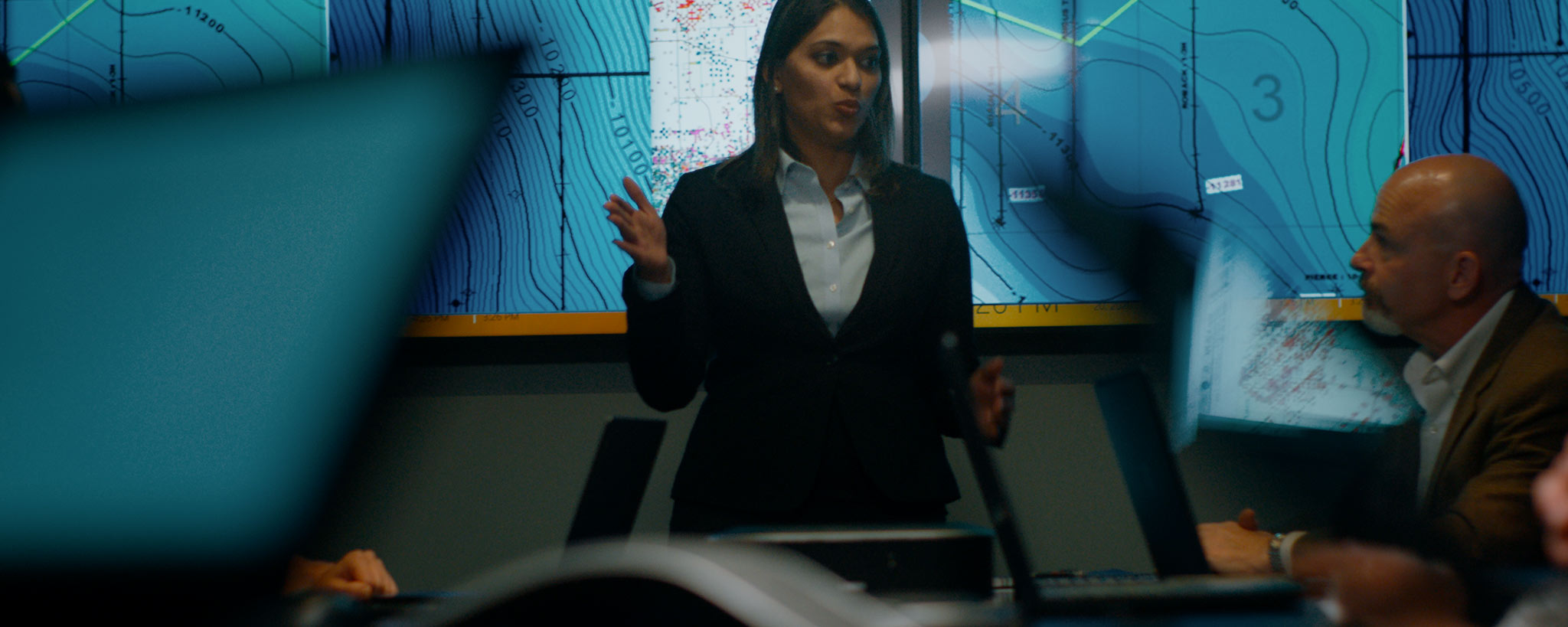 Female leading a group meeting with maps on screen