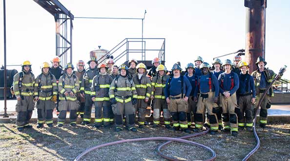 A group of first responders stand in front of oil well machinery