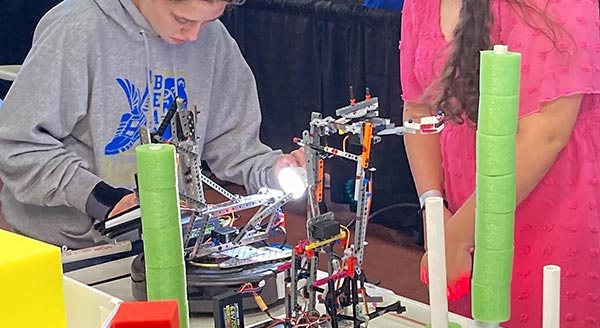 A student and teacher work together on a robotics experiment