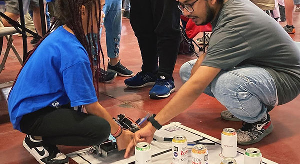 A volunteer helps a student with a Botball experiment