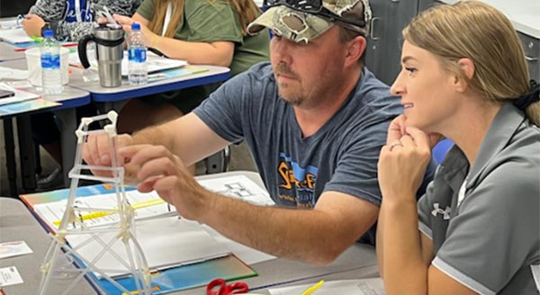 Two workshop participants build a structure with plastic straws