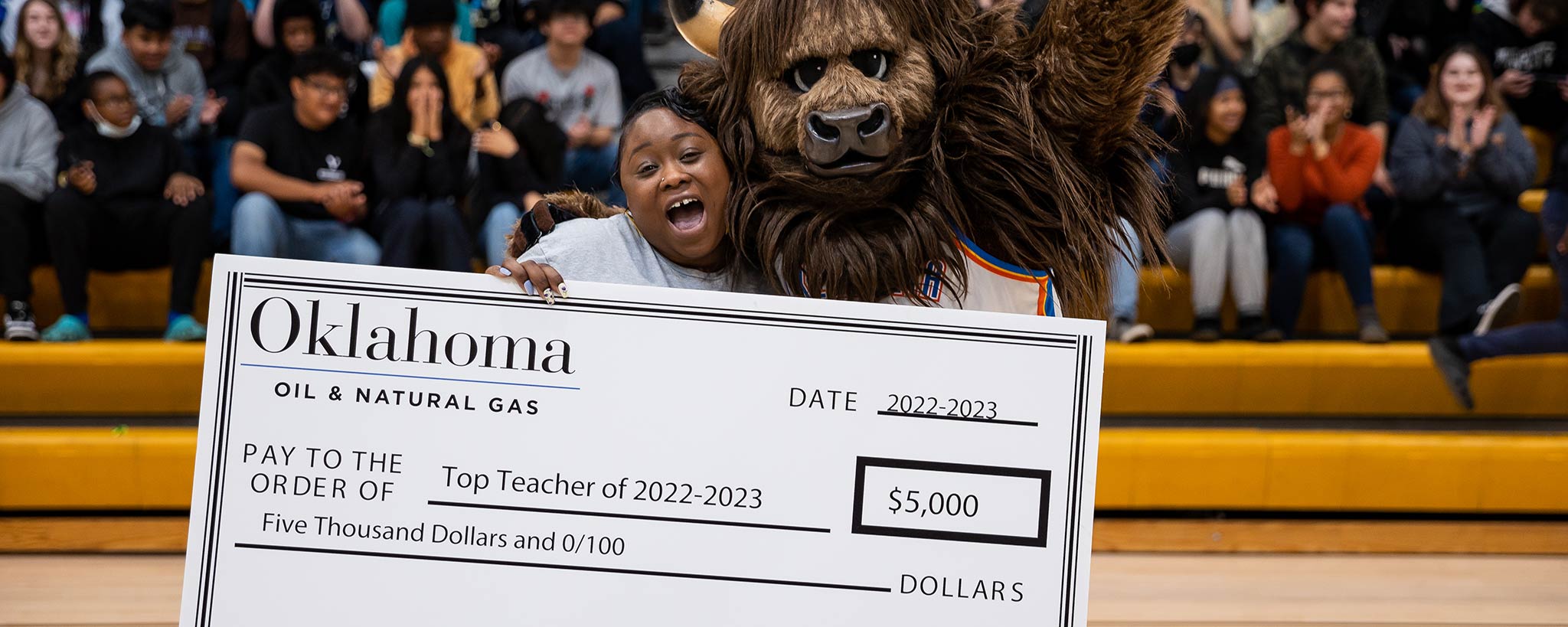 Top Teacher of 2022-2023 in arena with mascot