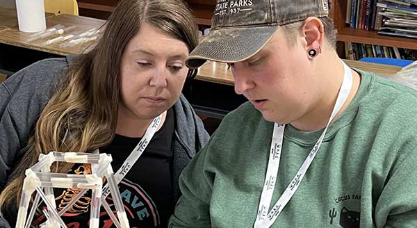 Two workshop participants experiment with building a structure out of straws