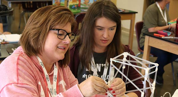 Two workshop participants experiment with building a straw structure