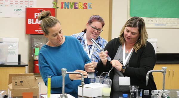 Three teachers experiment with a syringe and liquids