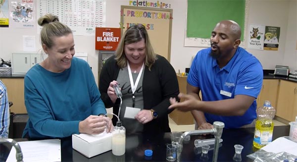 Three workshop participants experiment with fluids in bottles