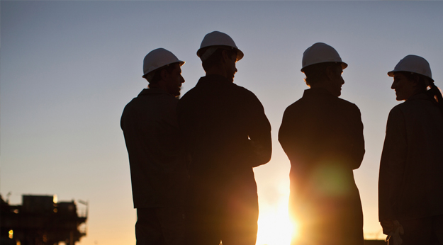 Oil technicians silhouetted against sunrise