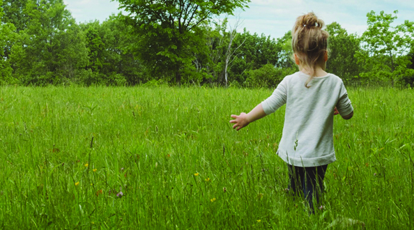 Child walking in grassy field