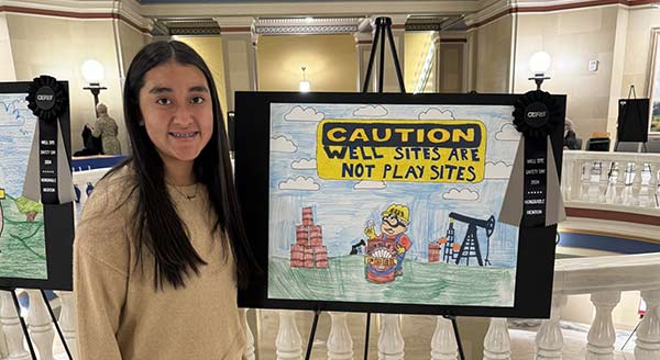 Well site safety winner with artwork depicting a caution sign with oil wells