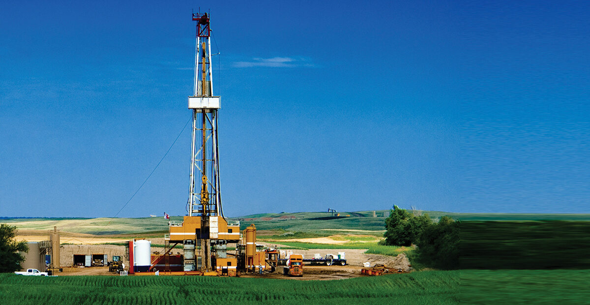 Oil drilling machinery in a green field with blue sky