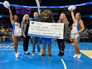 Taylor Painter holding Top 20 Teacher award check with Oklahoma City Thunder mascot and cheerleaders