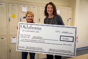 Julie Rother holds an award check for Top Ten Teacher of 2022